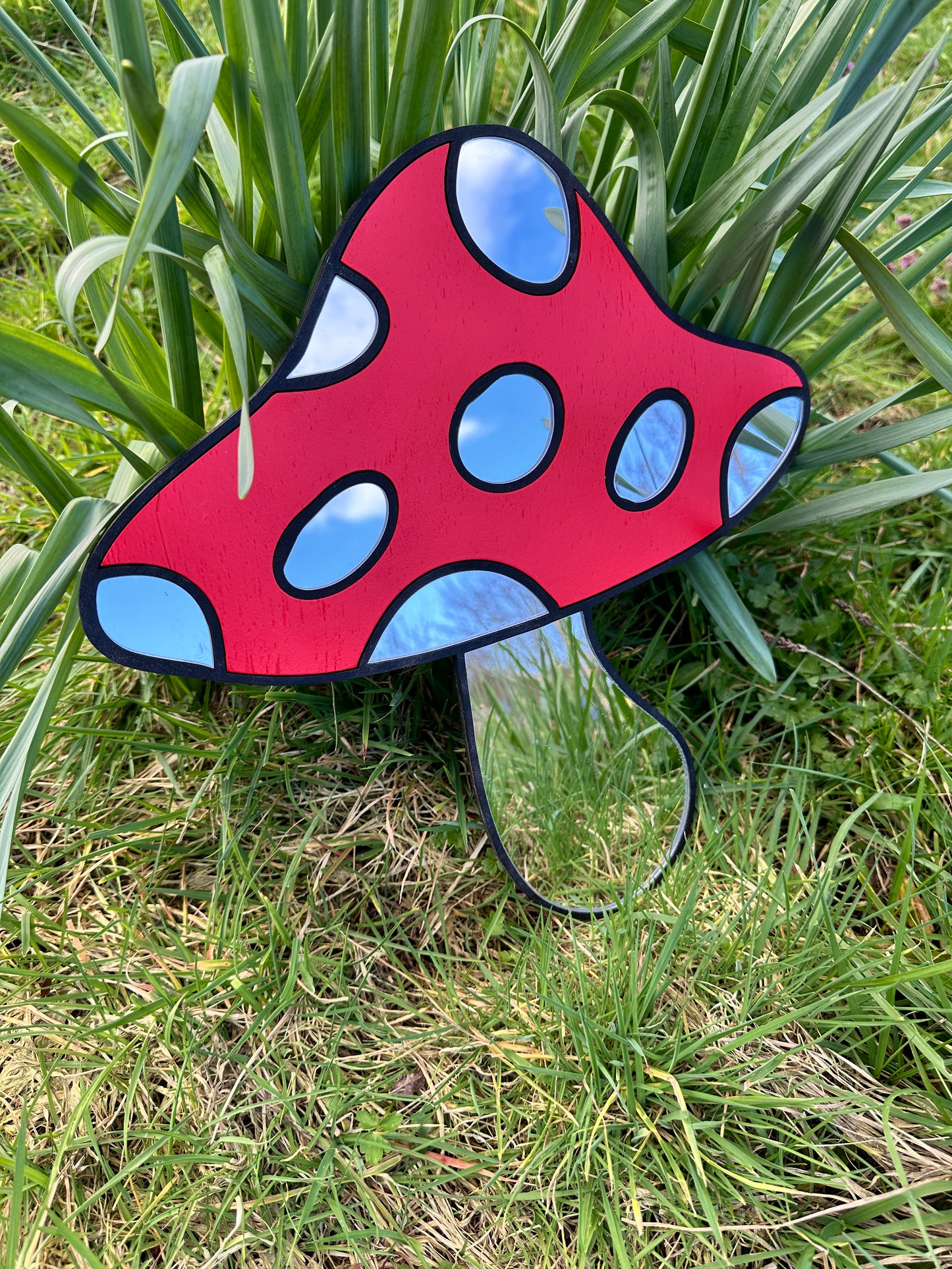 Red and blue decorative mushroom-shaped object on grass